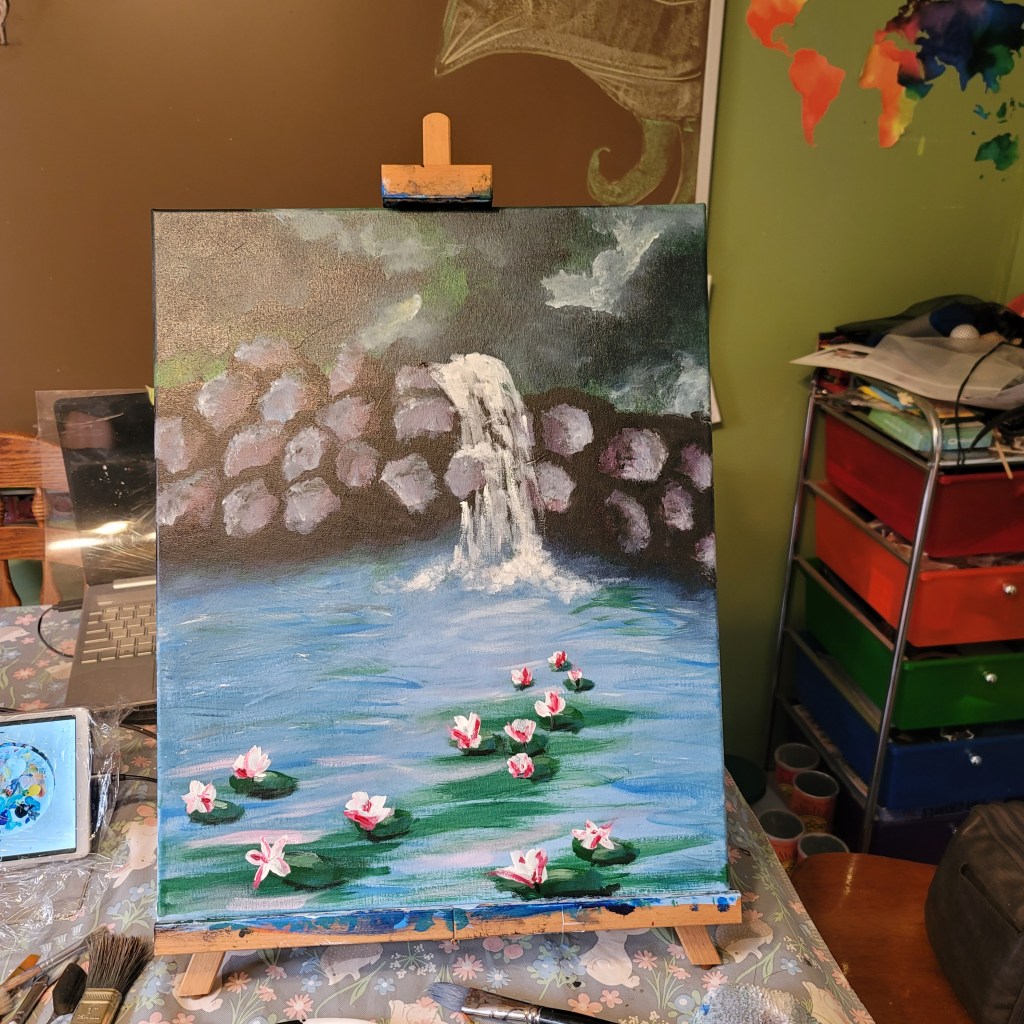 A colorful painting depicting a serene water scene with a small waterfall, lily pads, and flowers in a pond. The artwork is displayed on an easel, surrounded by painting materials.